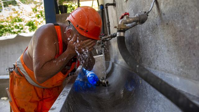 Un ouvrier s'hydrate sur un chantier au Tessin. [Keystone - Ti-Press/Francesca Agosta]