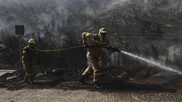 Des pompiers en intervention dans le feu de forêt qui s'est déclaré près de la banlieue sud d'Athènes. [AP/Keystone - Yorgos Karahalis]