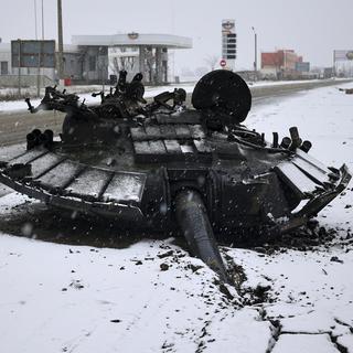 Les restes d'un char russe brûlé sont laissés à l'abandon après une attaque de l'armée ukrainienne près de la ville de Kharkiv, le 25 février 2022. [keystone - Sergey Kozlov]