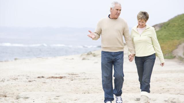 Un couple de senior se promène sur la plage. [Depositphotos - monkeybusiness]