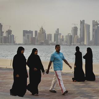 Des femmes et un homme se baladent au bord de la mer de Doha, Qatar. [Keystone - AP Photo/Kamran Jebreili]