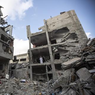 Des Palestiniens fouillent les décombres d'un bâtiment dans lequel un haut militant du Jihad a été tué suite à une frappe aérienne israélienne à Rafah, dans le sud de la bande de Gaza, dimanche 7 août 2022. [AP Photo/Keystone - Yousef Masoud]