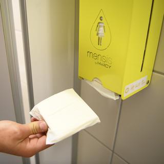 Un distributeur de serviette hygiéniques dans les toilettes d'un collège. [Keystone - Laurent Gillieron]