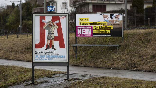 Des affiches en faveur et contre le paquet d'aide aux médias photographiés à Wallisellen (ZH). [Keystone - Christian Beutler]