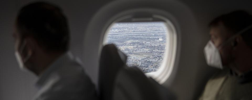 Des passagers portant un masque dans un avion. [Keystone - Christian Beutler]