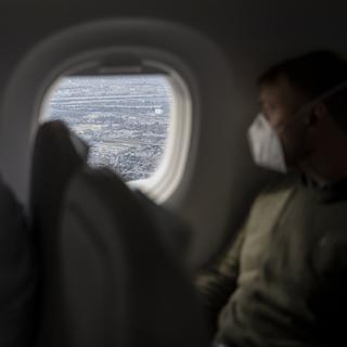 Des passagers portant un masque dans un avion. [Keystone - Christian Beutler]