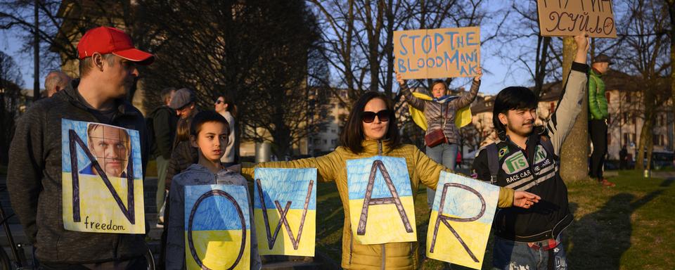 Des manifestants portent des pancartes portant l'inscription "Non à la guerre" alors qu'ils participent à une manifestation contre l'invasion de l'Ukraine par la Russie à Lausanne. [Keystone - Laurent Gillieron]