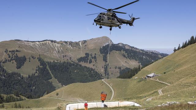 Un hélicoptère Super Puma de l'armée suisse ravitaille en eau l'alpage de Tissiniva, le 10 août 2022, à Charmey. [KEYSTONE - Cyril Zingaro]