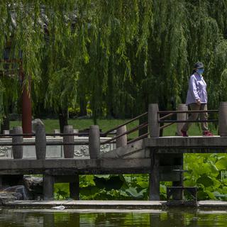 Une femme portant un masque dans un parc à Pékin. [Keystone - Mark Schiefelbein/AP Photo]
