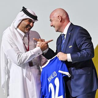 Le président de la FIFA Gianni Infantino remet un maillot au Premier ministre du Qatar. [Keystone - EPA/Noushad Thekkayil]