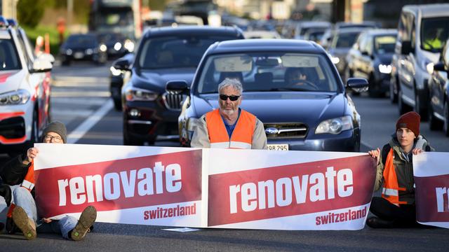 Des militants de Renovate Switzerland lors d'une action de blocage sur l'autoroute A1 à Lausanne le 11 avril 2022. [Keystone - Laurent Gilliéron]