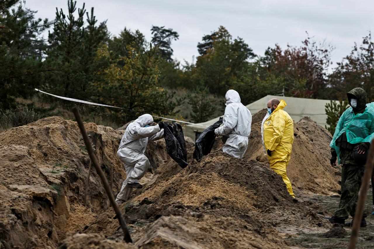 Des médecins légistes transportent le corps d'un officier de l'armée qu'ils ont exhumé d'une fosse commune à Lyman, le 11 octobre 2022. [REUTERS - ZOHRA BENSEMRA]