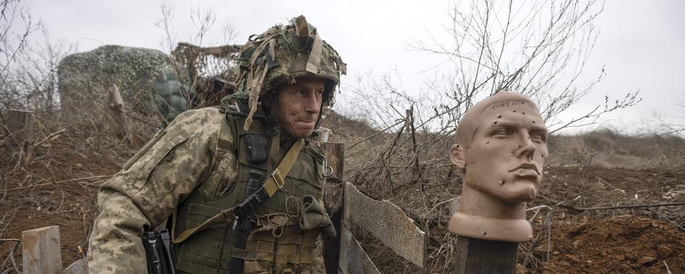 Un soldat ukrainien marche dans une tranchée à la ligne de séparation des rebelles pro-russes, région de Donetsk, Ukraine, dimanche 9 janvier 2022. [AP Photo/KEYSTONE - Andriy Dubchak]