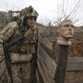 Un soldat ukrainien marche dans une tranchée à la ligne de séparation des rebelles pro-russes, région de Donetsk, Ukraine, dimanche 9 janvier 2022. [AP Photo/KEYSTONE - Andriy Dubchak]