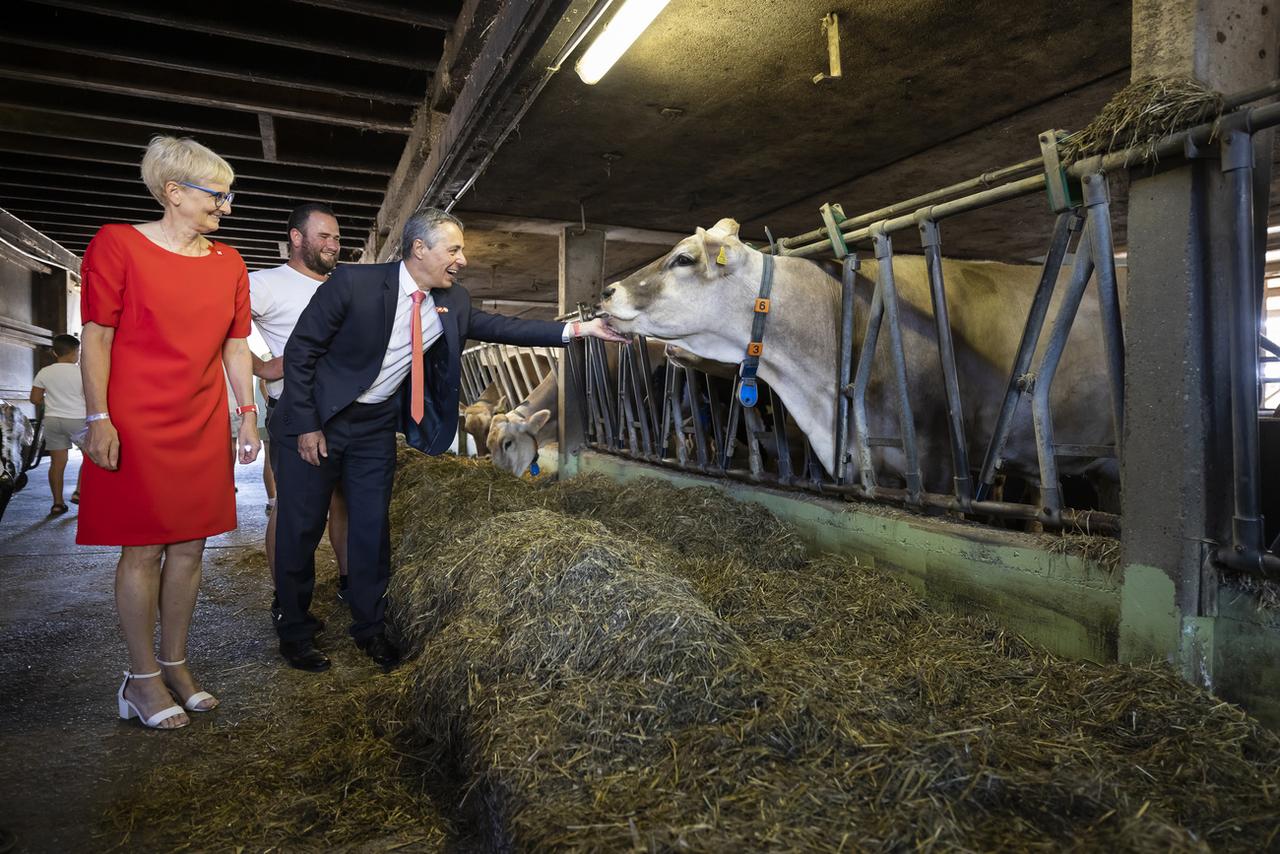 Le président de la Confédération Ignazio Cassis, son épouse Paola Rodoni et l'exploitant Serge Duperrex lors d'un brunch à la ferme Stöckweid, à Knonau (ZH), à l'occasion du 1er Août. [KEYSTONE - Michael Buholzer]