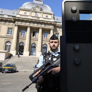 Un policier se tient devant le palais de justice de Paris, où se tient le procès des attentats terroristes du 13 novembre 2015 à Paris. [Keystone - AP Photo/Francois Mori]