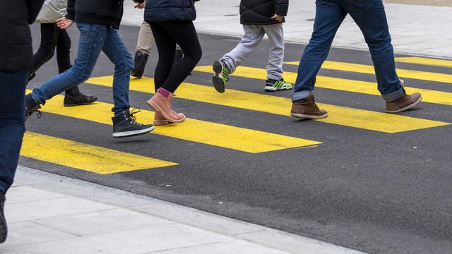 Des personnes traversant une route sur un passage piéton à Genève. [Keystone - Martial Trezzini]