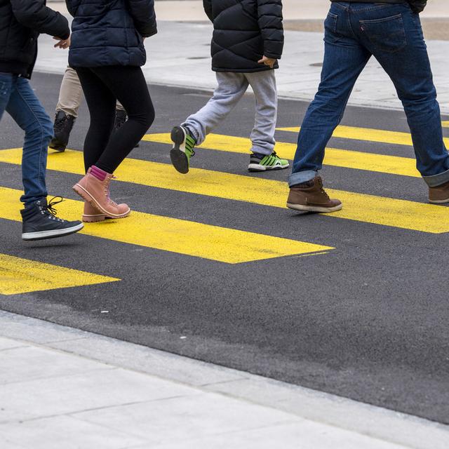 Des personnes traversant une route sur un passage piéton à Genève. [Keystone - Martial Trezzini]