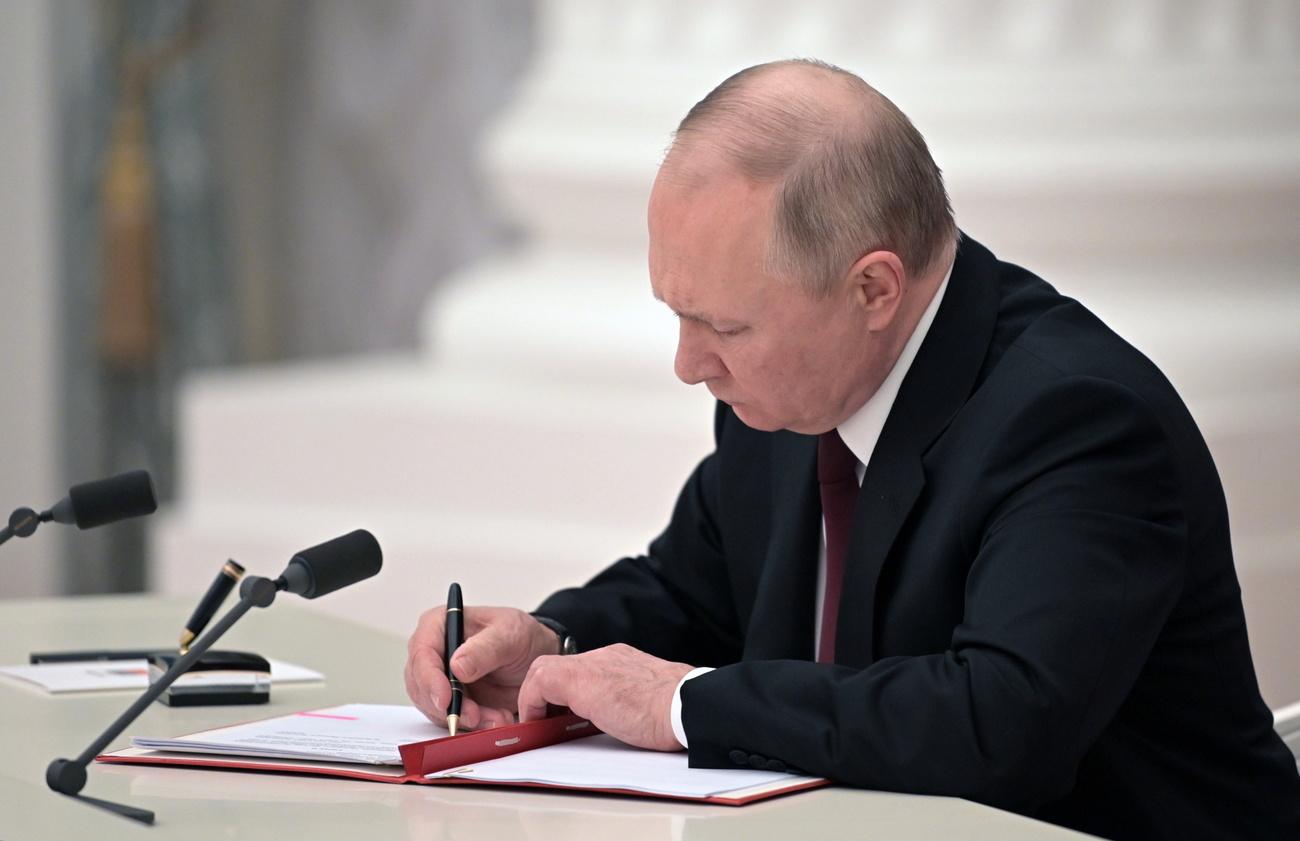 Vladimir Poutine signant le décret reconnaissant l'indépendance des entités prorusses de l'Est de l'Ukraine. [Kremlin Pool/Sptunik/EPA/Keystone - Aleksey Nikolskyi]