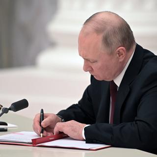 Vladimir Poutine signant le décret reconnaissant l'indépendance des entités prorusses de l'Est de l'Ukraine. [Kremlin Pool/Sptunik/EPA/Keystone - Aleksey Nikolskyi]