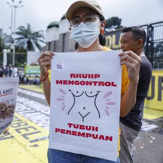 Des manifestantes indonésiennes tiennent des pancartes indiquant que "le droit pénal contrôle le corps des femmes" lors d'une mobilisation contre le nouveau code le 5 décembre à Jakarta. [Keystone - EPA/MAST IRHAM]