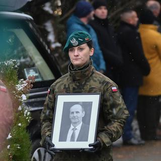 Une garde frontières polonaise tient la photo d'une des victimes du tir de missile. [AP Photo/Keystone]