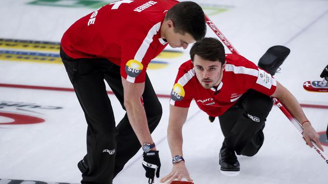 Le quatrième Suisse Benoit Schwarz, à droite, effectue un tir alors que le meneur Valentin Tanner balaie contre l'Italie lors des Championnats du monde de curling masculin à Calgary, Alberta, lundi 5 avril 2021. [The Canadian Press via AP/KEYSTONE - Jeff McIntosh]