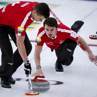 Le quatrième Suisse Benoit Schwarz, à droite, effectue un tir alors que le meneur Valentin Tanner balaie contre l'Italie lors des Championnats du monde de curling masculin à Calgary, Alberta, lundi 5 avril 2021. [The Canadian Press via AP/KEYSTONE - Jeff McIntosh]