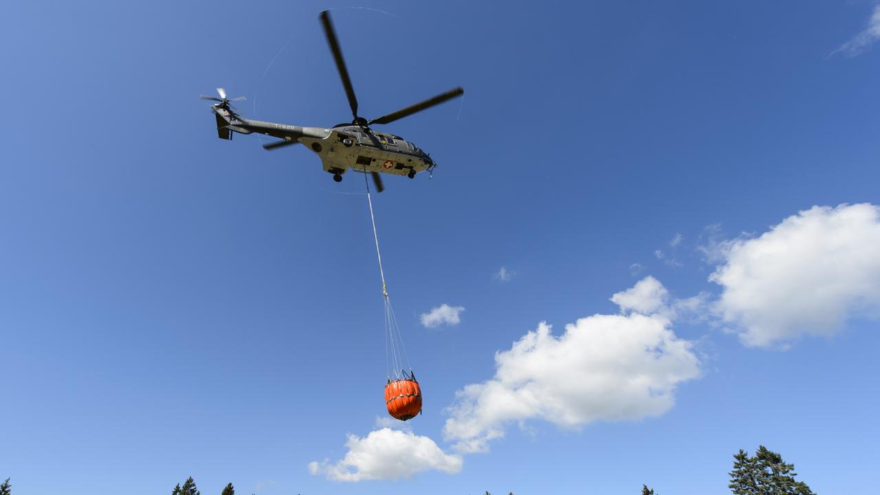 Un Super Puma de l'armée suisse transportant une charge d'eau (image d'illustration). [Keystone - Jean-Christophe Bott]