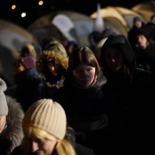 Des réfugiés fuyant la guerre dans l'Ukraine voisine passent devant des tentes après avoir traversé vers Medyka, en Pologne, mercredi 9 mars 2022. [AP Photo/KEYSTONE - Daniel Cole]