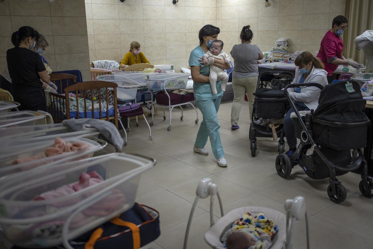 Des soignantes prennent soin de bébés nés de mères porteuses, dans une cave de Kiev, le 19 mars 2022. [AP/Keystone - Rodrigo Abd]
