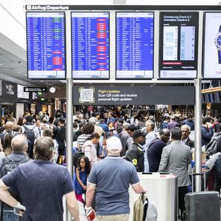 Des passagers photographiés à l'aéroport de Zurich au moment où les vols commencent à reprendre après une panne informatique qui a touché Skyguide. [Keystone - Ennio Leanza]