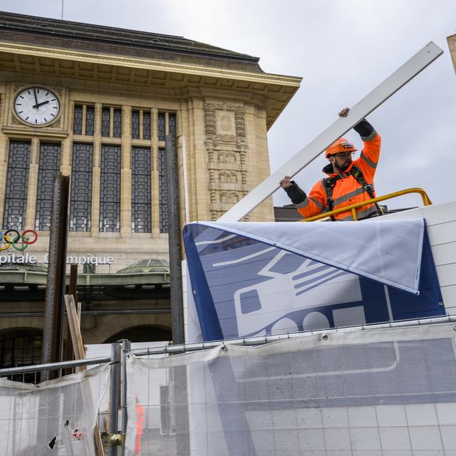 Un ouvrier démonte la palissade de chantier devant la gare de Lausanne. [Keystone - Jean-Christophe Bott]