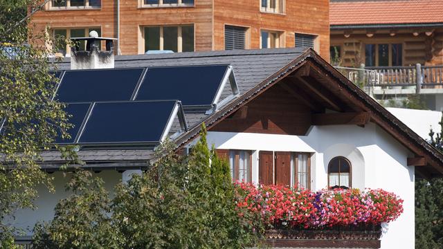 Panneaux solaires sur le toit d'une maison à Flerden, dans les Grisons. [Keystone - Gaëtan Bally]