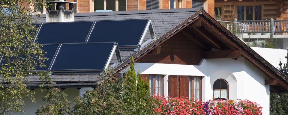 Panneaux solaires sur le toit d'une maison à Flerden, dans les Grisons. [Keystone - Gaëtan Bally]