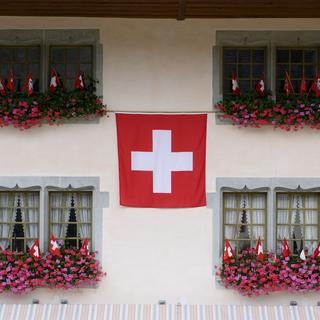 Un drapeau suisse est photographié sur la façade d'un bâtiment lors des festivités du 1er août, à Gruyères. [KEYSTONE - Anthony Anex]