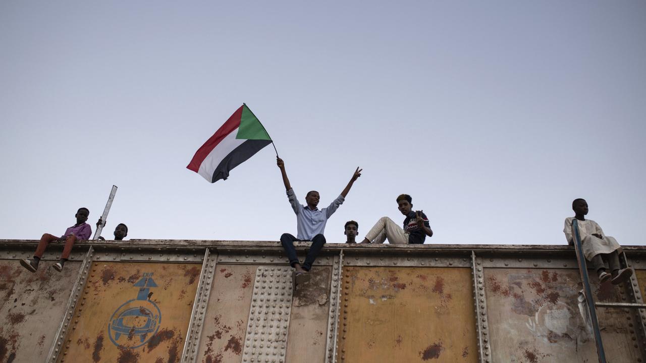Un manifestant brandit un drapeau soudanais lors d'un sit-in sur la place des forces armées à Khartoum, au Soudan, le 27 avril 2019. [KEYSTONE - Salih Basheer / AP Photo]