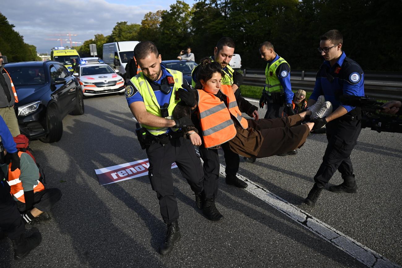 Des membres de Renovate Switzerland se sont assis sur la route lors d'une action de blocage de l'autoroute A1 à l'entrée de Lausanne. [Keystone - Laurent Gillieron]