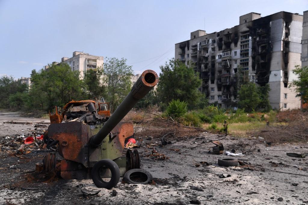 Un canon détruit par des bombardements, devant des immeubles en ruines, le 11 juin 2022 à Severodonetsk. [AFP - Viktor Antonyuk]