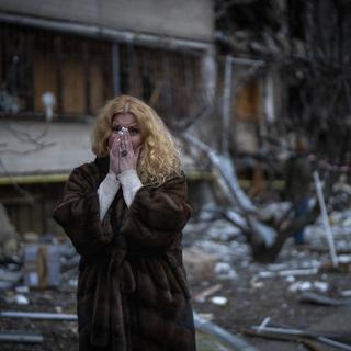 Une femme devant sa maison détruite par une attaque à Kiev. [AP Photo/Keystone - Emilio Morenatti]