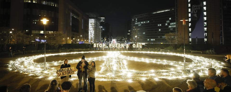 Un réfugié ukrainien participe à une campagne d'Aavaz montrant un signe de paix géant et l'huile Stop Poutine lors d'une manifestation contre l'invasion russe de l'Ukraine à Bruxelles, en Belgique, le 22 mars 2022. [KEYSTONE - Olivier Hoslet]