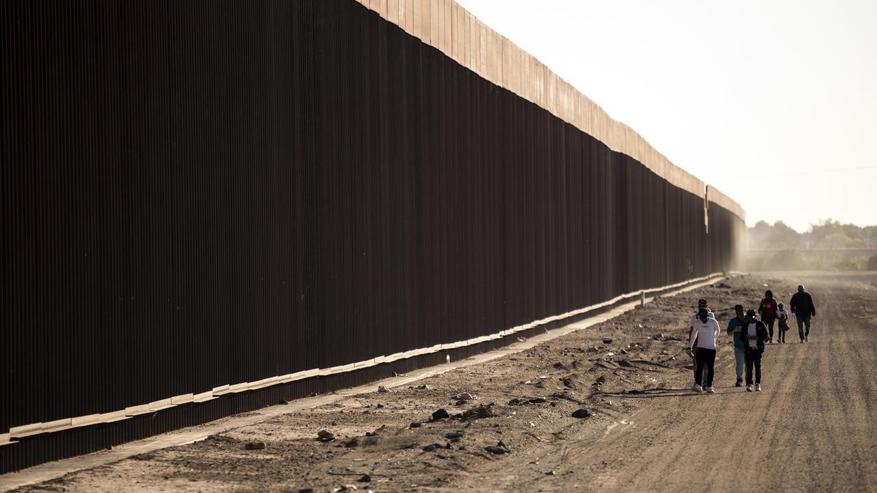 Des migrants de la République dominicaine marchent du côté mexicain de la frontière avec les États-Unis, vers une ouverture dans la clôture, à Yuma, Arizona, le 28 octobre 2022. [KEYSTONE - Etienne Laurent / EPA]
