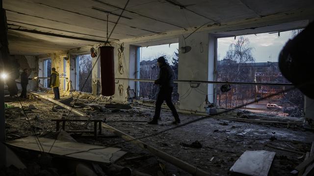 Des résidents locaux nettoient les débris d'une salle d'escrime détruite lors d'un bombardement dans le centre-ville de Donetsk, en Ukraine, le 09 décembre 2022. [Keystone]