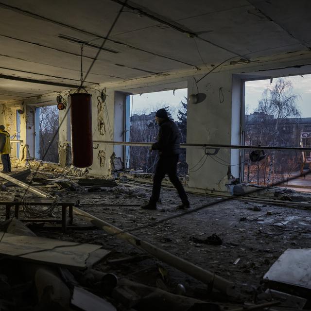 Des résidents locaux nettoient les débris d'une salle d'escrime détruite lors d'un bombardement dans le centre-ville de Donetsk, en Ukraine, le 09 décembre 2022. [Keystone]
