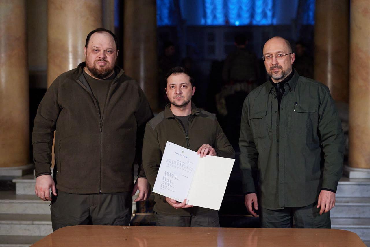 Volodymyr Zelensky entouré du président de la Rada Rouslan Stefantchouk (à g.) et du Premier ministre Denys Shmyhal  (à dr.). [EPA/Keystone - TELEGRAM/V_ZELENSKIY_OFFICIAL /]