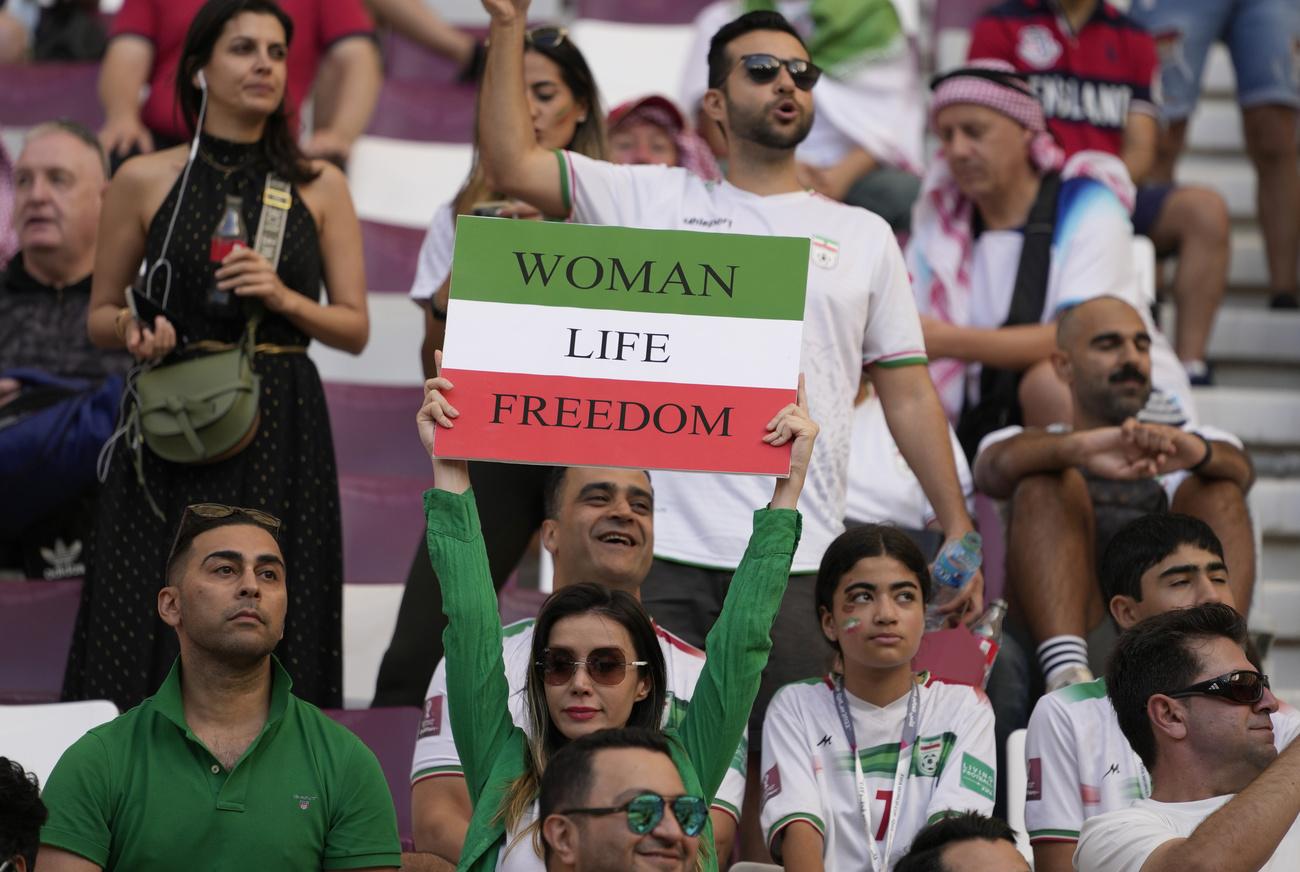 Une supportrice iranienne tenant une pancarte "Woman Life Freedom" le 21 novembre 2022 lors du match entre l'Iran et l'Angleterre au Mondial 2022 à Doha. [KEYSTONE - ALESSANDRA TARANTINO]