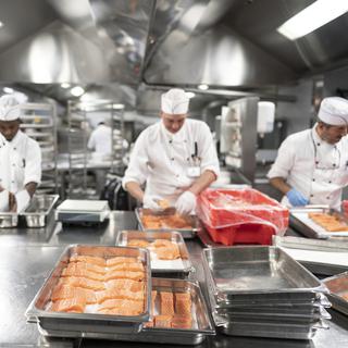 Des cuisiniers préparent du saumon frais pour le service de midi dans la cuisine du Centre hospitalier universitaire vaudois (CHUV), à Lausanne. [Keystone - Gaetan Bally]