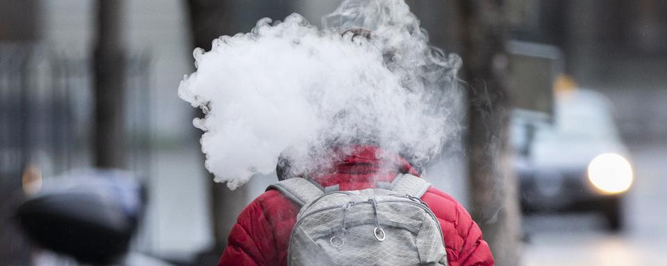 Un passant fume une e-cigarette, le vendredi 4 décembre 2020 à Berne. [KEYSTONE - Peter Klaunzer]