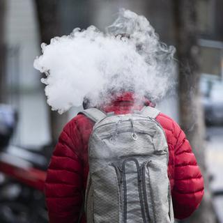 Un passant fume une e-cigarette, le vendredi 4 décembre 2020 à Berne. [KEYSTONE - Peter Klaunzer]