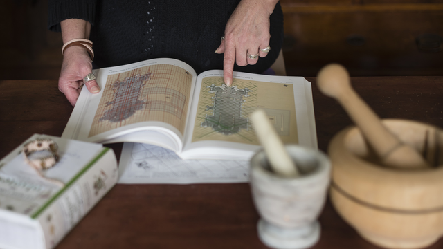 Une sorcière avec un livre et des instruments à préparer les potions. La sorciere Laurence Blum nous presente un plan pour nous expliquer les failles souterraines lors de l interview pour le deplacement de la croix du village dans son atelier a Courtedoux ce lundi 02 Mai 2016. (KEYSTONE/Stefan Meyer) [KEYSTONE - Stefan Meyer]